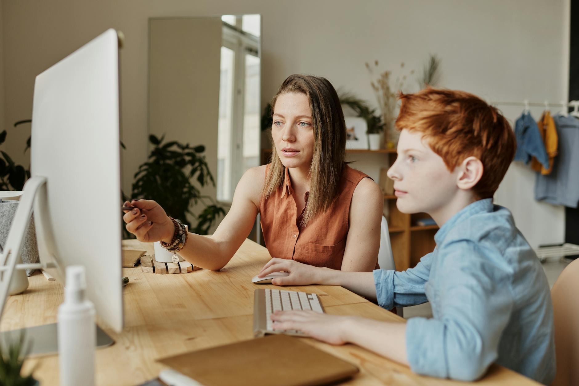 Mama pomaga synowi w nauce online przy komputerze w domu