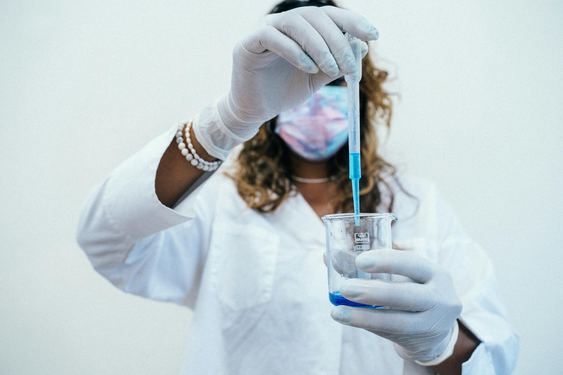 Studentka w fartuchu w laboratorium używa pipety do próby chemicznej