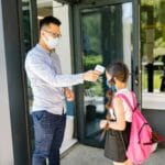 Nauczycielka mierzy temperaturę uczennicy przy wejściu do szkoły