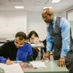 Nauczycielka nadzoruje studentów piszących test w sali wykładowej