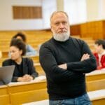 Wykładowca na tle słuchających studentów w auli uczelni