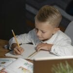 Jak planować naukę w rytmie dziecka: odblokowanie ciekawości bez „przerabiania” podręcznika Chłopiec odrabiający lekcje przy biurku w domowym zaciszu