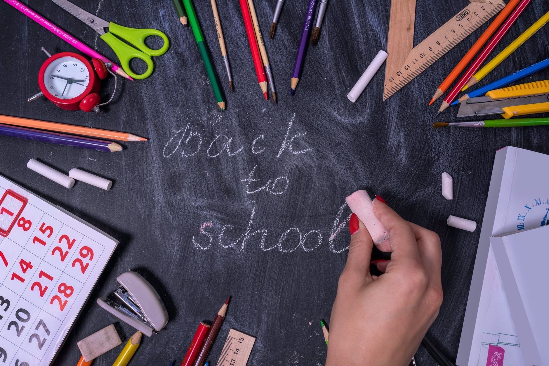 Napis back to school na tablicy i rozłożone przybory szkolne
