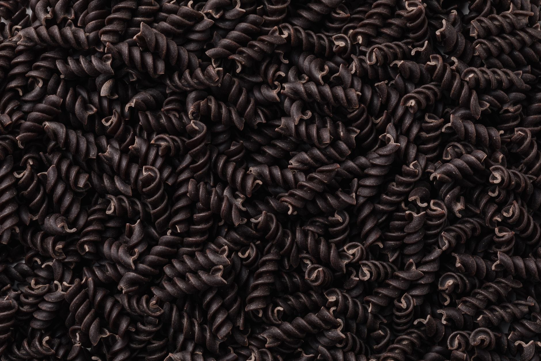 Surowy ciemny makaron fusilli z czarnej fasoli z bliska